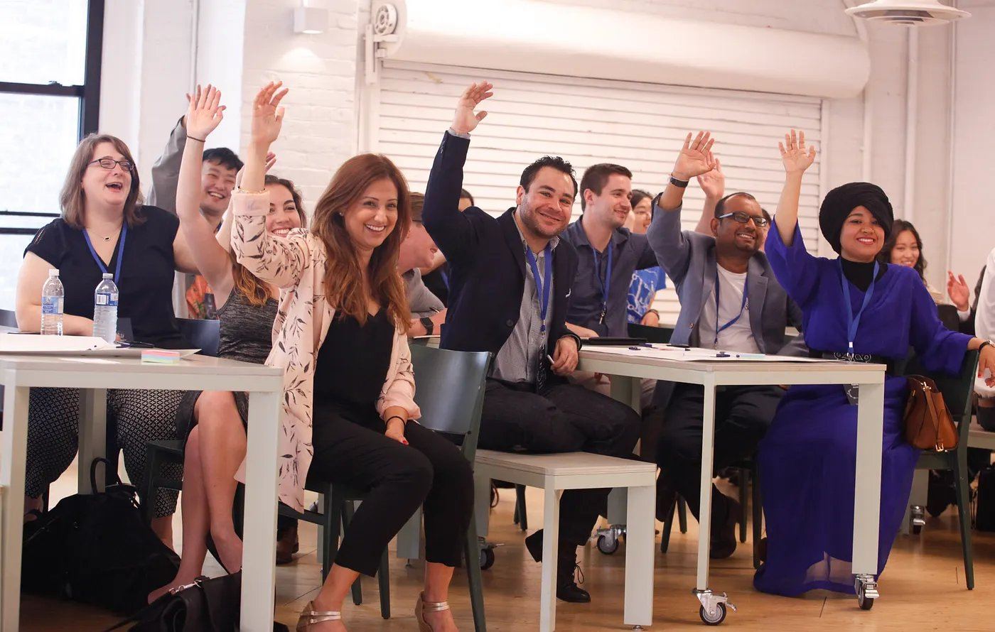 Delegates laughing with hands raised in a workshop