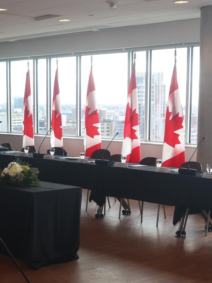 A row of Canadian flags at a staged head table overlooking the city
